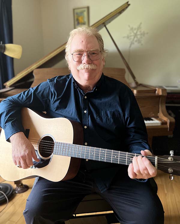 mr hooper happily holding his guitar